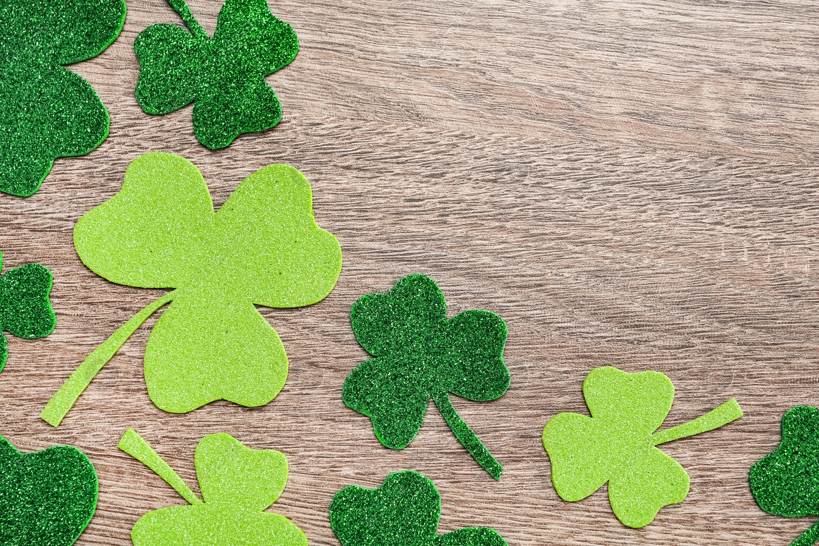 Photo of Decorative clover leaves on grey wooden table, flat lay with space for text. Saint Patrick's Day celebration