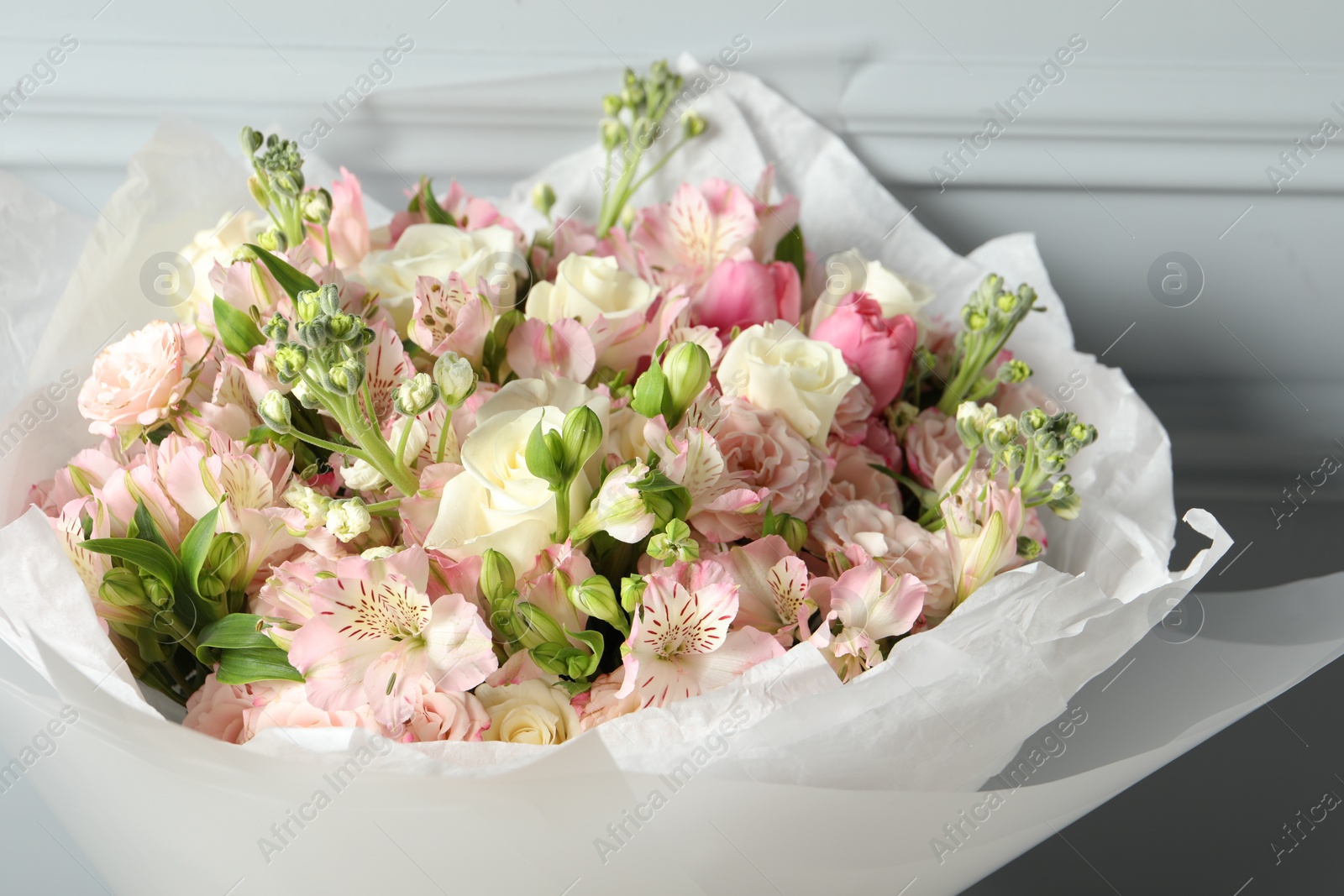 Photo of Beautiful bouquet of fresh flowers near grey wall, closeup