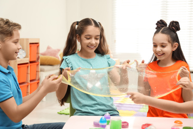 Photo of Happy children playing with slime at table indoors