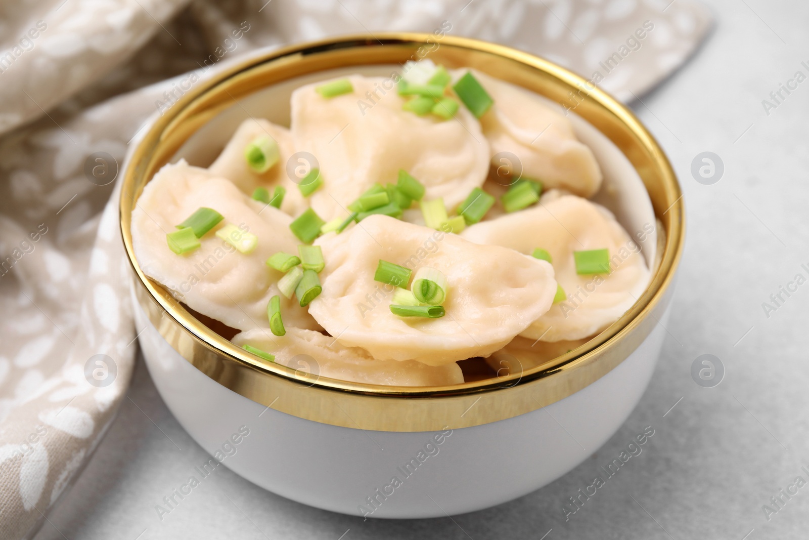 Photo of Cooked dumplings (varenyky) with tasty filling and green onion on light table, closeup