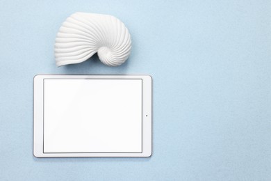Photo of Modern tablet and sea shell on light background, flat lay. Space for text