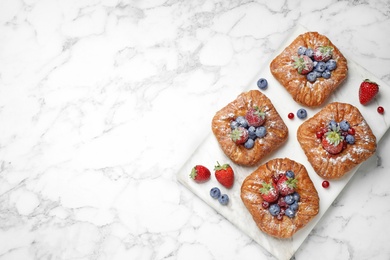 Photo of Fresh delicious puff pastry with sweet berries on white marble table, top view. Space for text