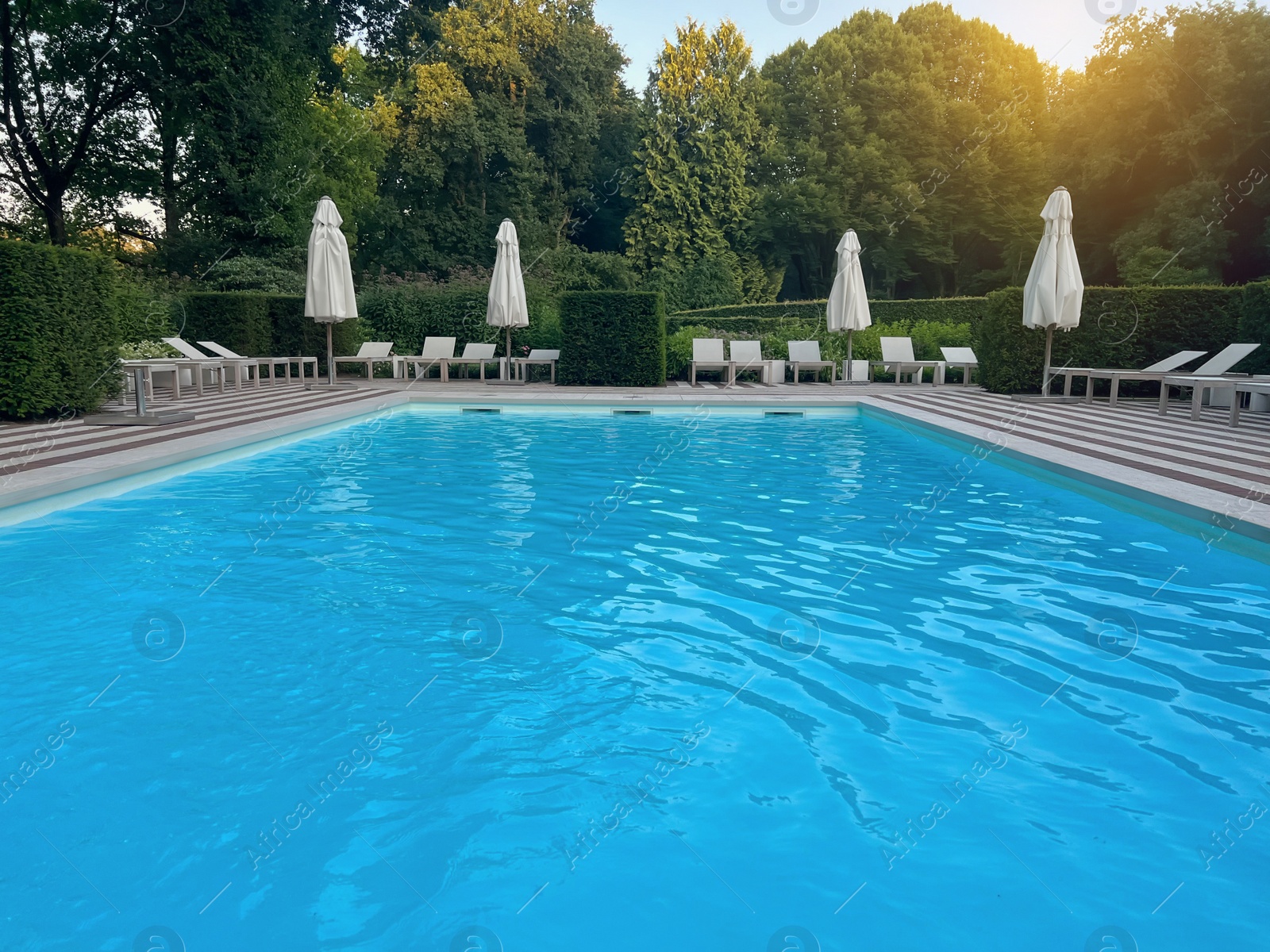 Photo of Outdoor swimming pool in luxury hotel on sunny summer day. Time for relax