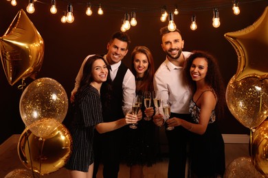 Photo of Happy friends with glasses of sparkling wine celebrating New Year indoors