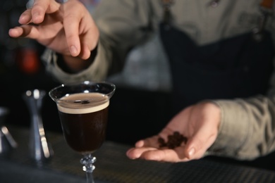 Photo of Barman adding coffee bean to martini espresso cocktail at counter, closeup. Space for text