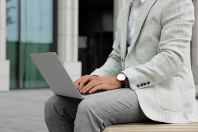 Photo of Businessman with laptop on city street, closeup
