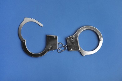 Photo of Classic chain handcuffs on blue background, top view