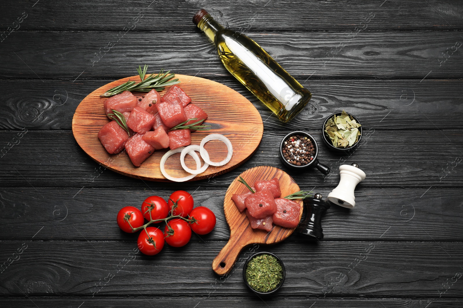 Photo of Raw beef meat and different ingredients for cooking delicious goulash on black wooden table, flat lay