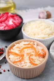 Photo of Delicious sauerkraut prepared according to different recipes on light gray table, closeup