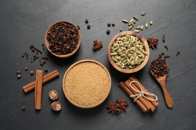 Photo of Different spices in bowls on dark gray textured table, flat lay