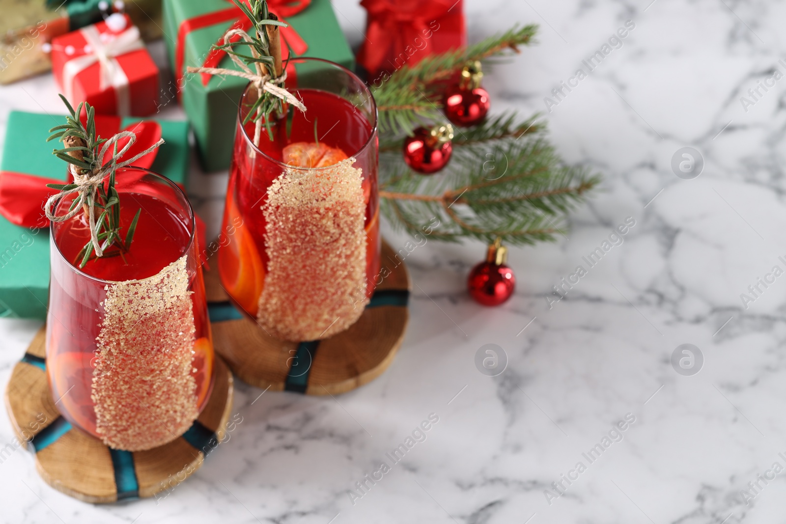 Photo of Christmas Sangria cocktail in glasses and festive decor on white marble table. Space for text