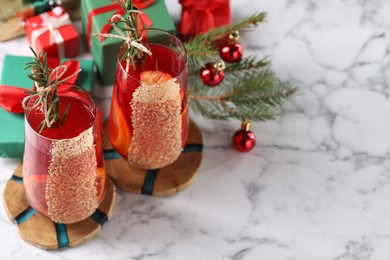 Photo of Christmas Sangria cocktail in glasses and festive decor on white marble table. Space for text