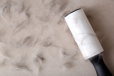 Modern lint roller and cat hair on light fabric, flat lay