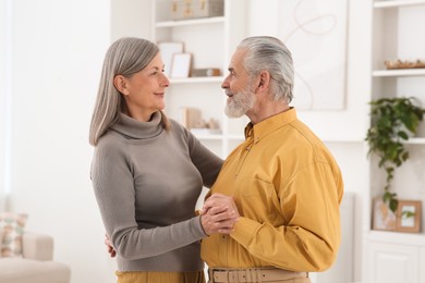 Photo of Affectionate senior couple dancing in living room at home