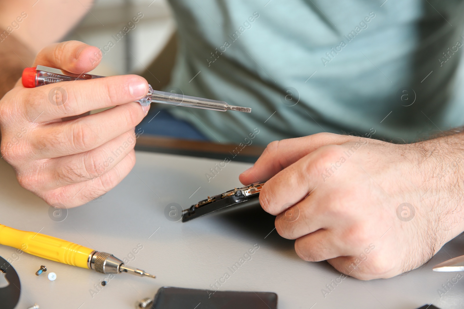 Photo of Technician repairing mobile phone at table, closeup