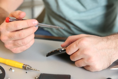 Photo of Technician repairing mobile phone at table, closeup