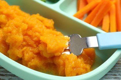 Photo of Baby food. Tasty pumpkin puree on wooden table, closeup