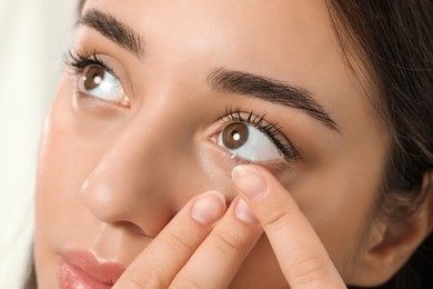 Photo of Woman putting contact lens in her eye, closeup view