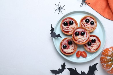 Photo of Cute monster tartlets served on white table, flat lay with space for text. Halloween party food