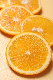 Slices of juicy orange and water on beige background, closeup