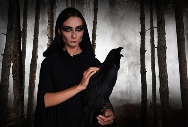 Mysterious witch with raven  in foggy forest. Fantasy world