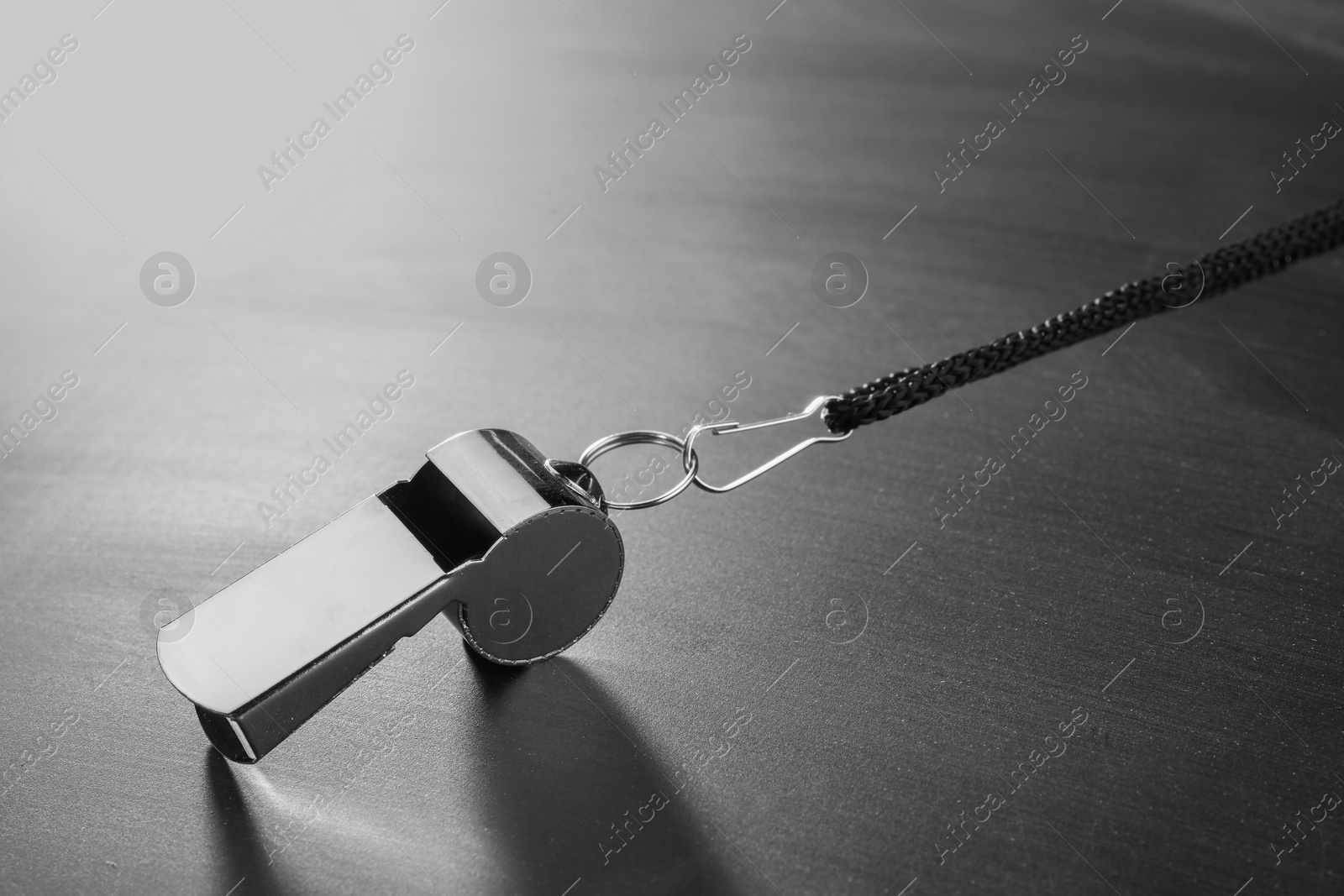 Photo of Referee equipment. Metal whistle on grey table, closeup and space for text
