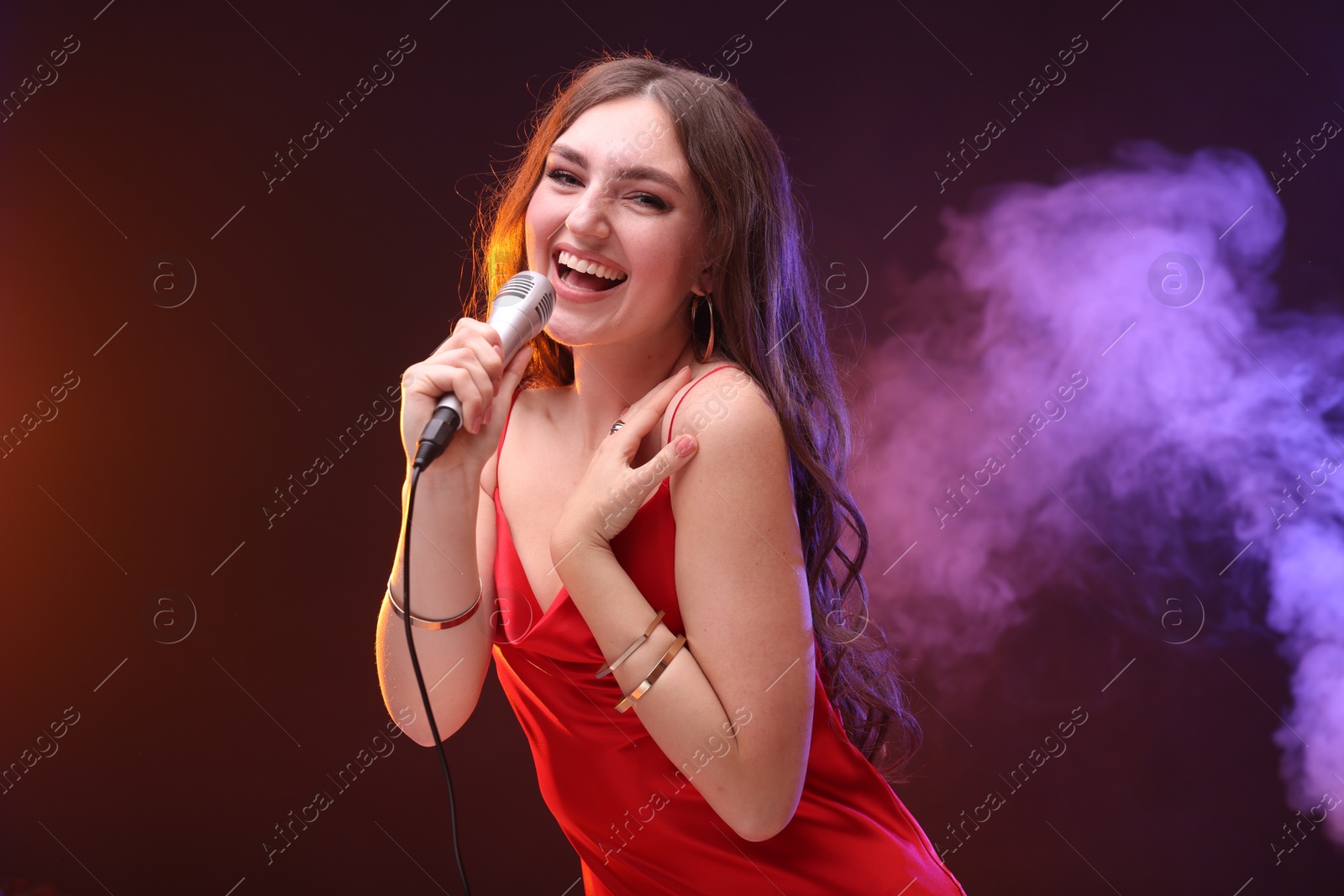 Photo of Emotional woman with microphone singing in color lights