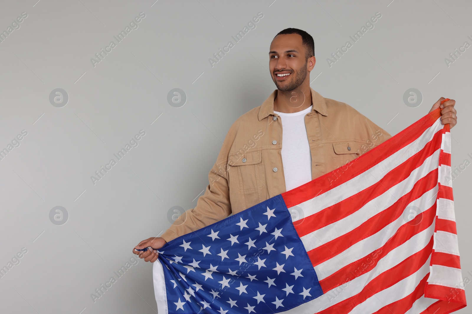 Photo of 4th of July - Independence Day of USA. Happy man with American flag on light grey background, space for text