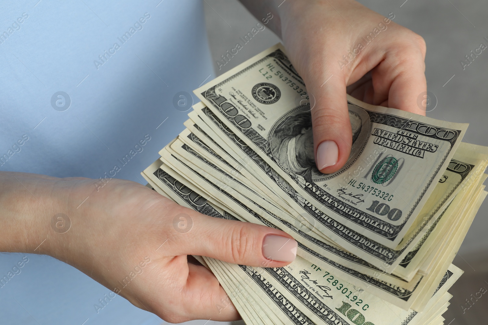 Photo of Money exchange. Woman counting dollar banknotes on grey background, closeup