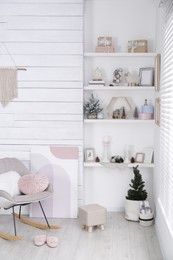 Photo of Stylish room interior with rocking chair, wall shelves and beautiful Christmas decor