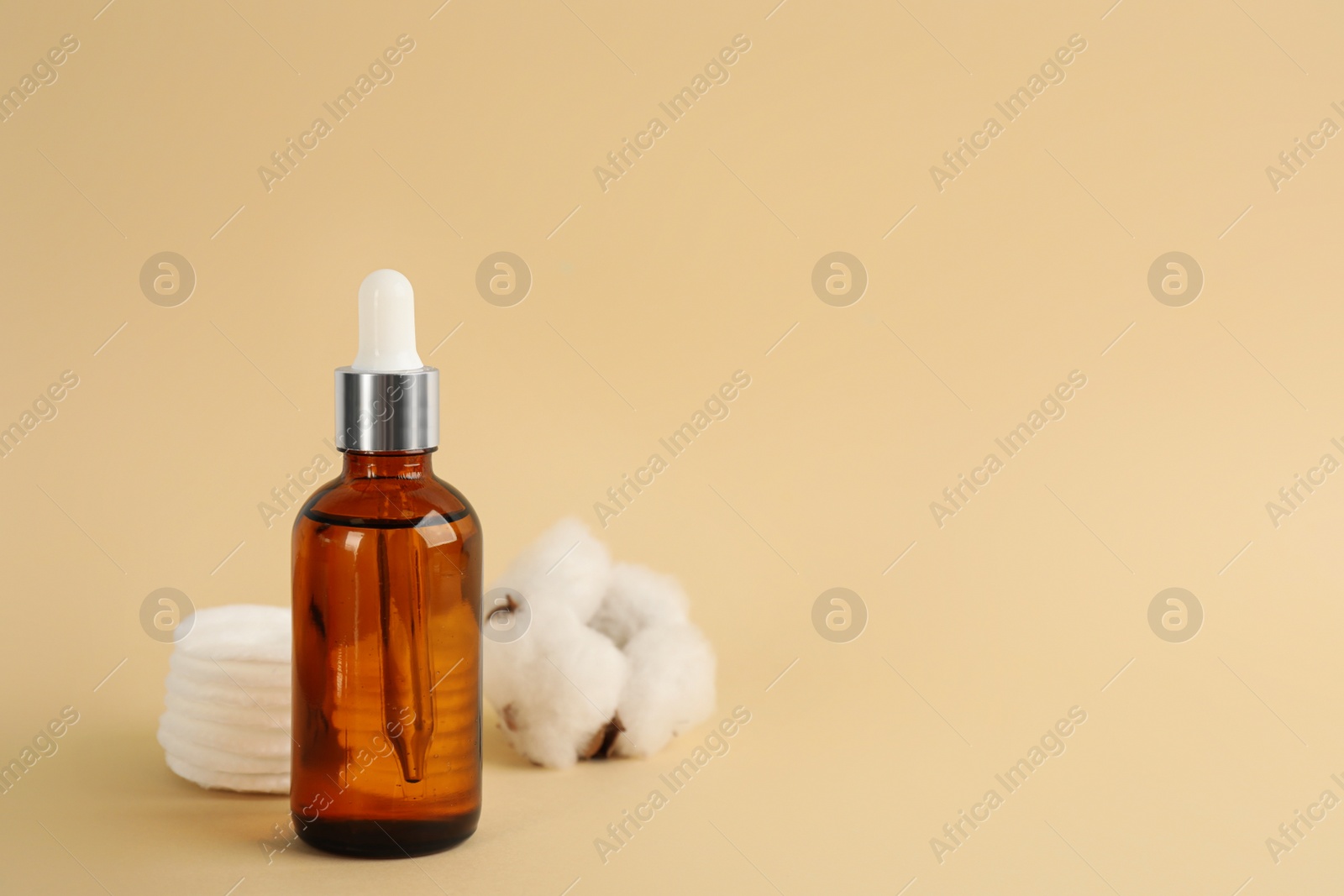 Photo of Cotton pads, flower and makeup removal product on beige background. Space for text