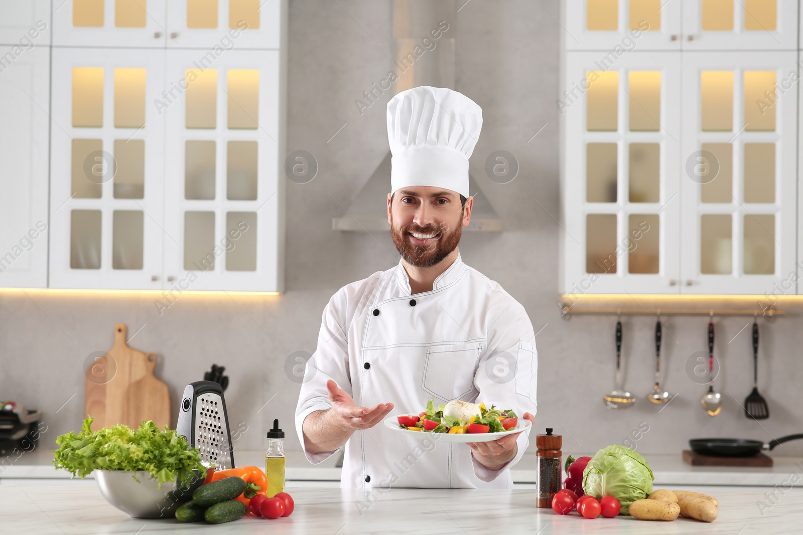 Photo of Professional chef presenting delicious salad at marble table in kitchen