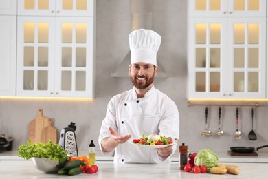 Professional chef presenting delicious salad at marble table in kitchen