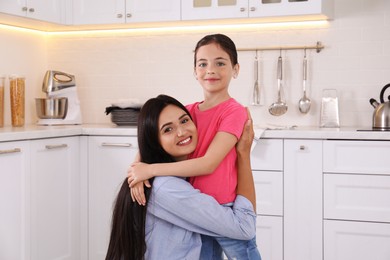 Portrait of happy mother and daughter hugging in kitchen. Single parenting