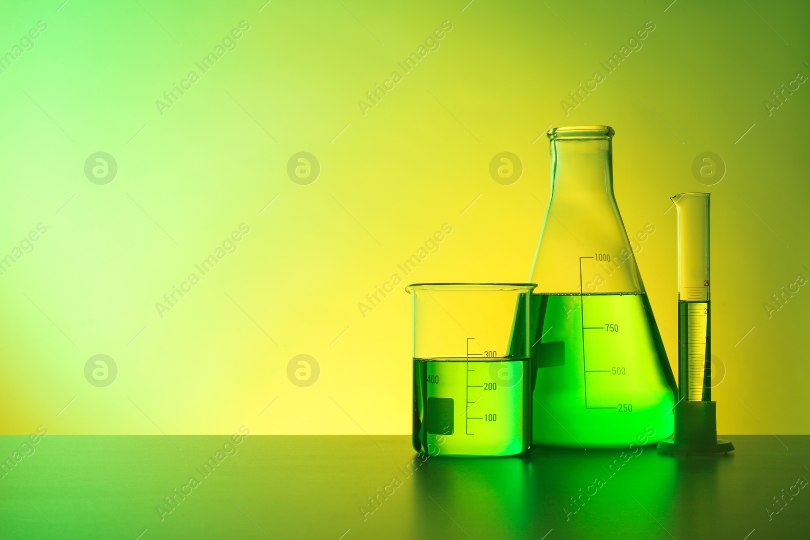 Photo of Chemistry laboratory glassware with samples on table against color background