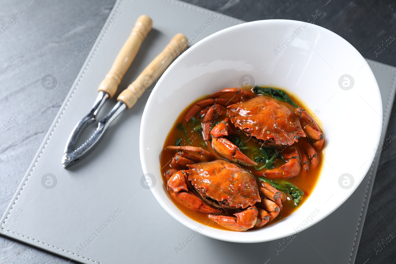 Photo of Delicious boiled crabs with sauce and cracker on grey table, above view