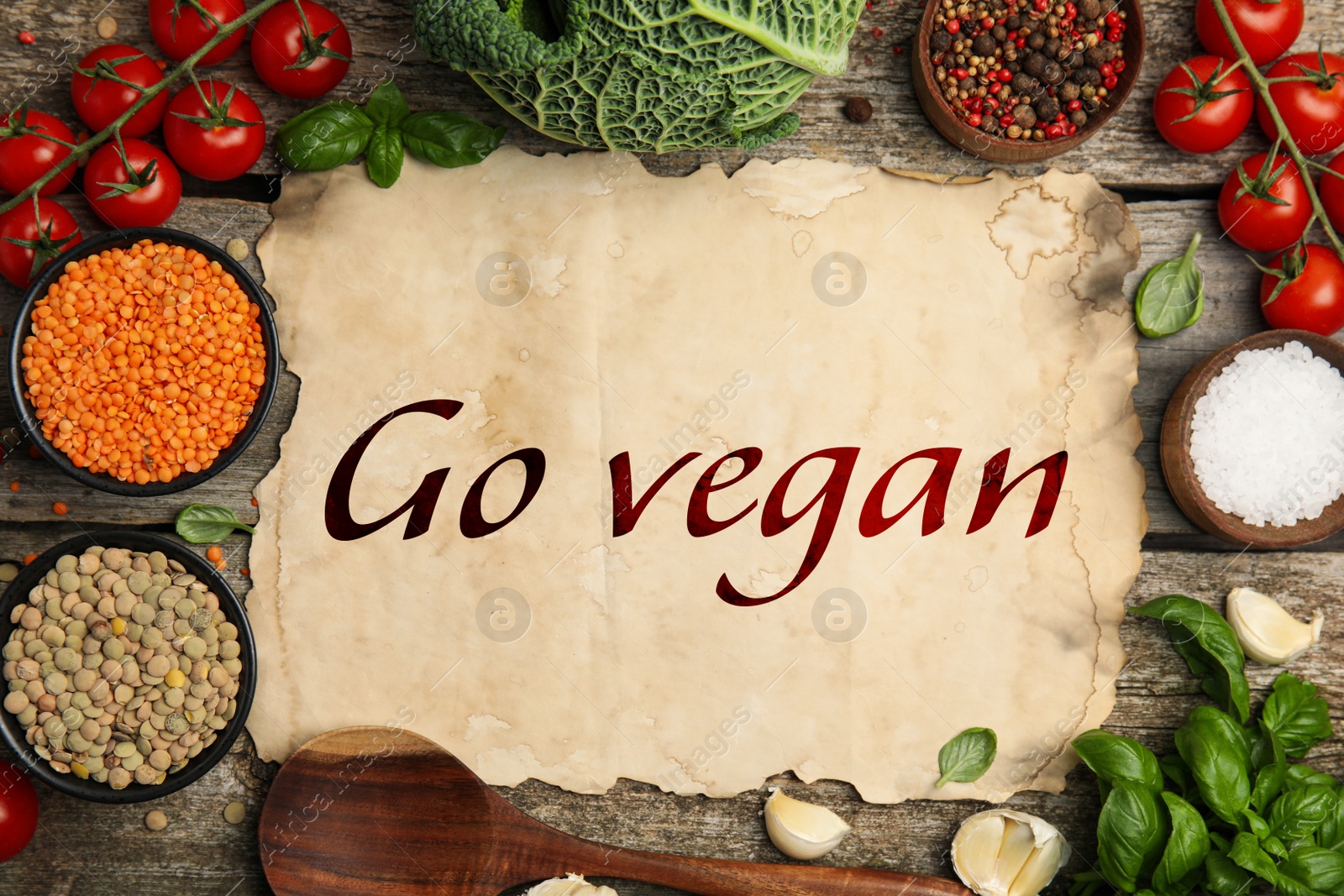 Image of Parchment paper with phrase Go Vegan and fresh products on wooden background, flat lay