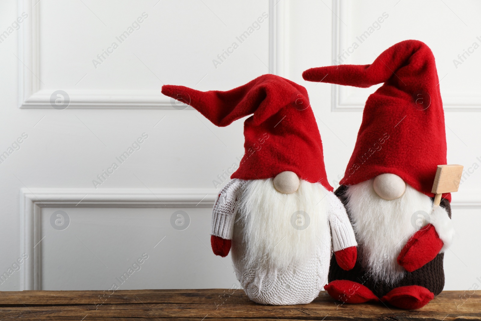 Photo of Two cute Christmas gnomes on wooden table. Space for text