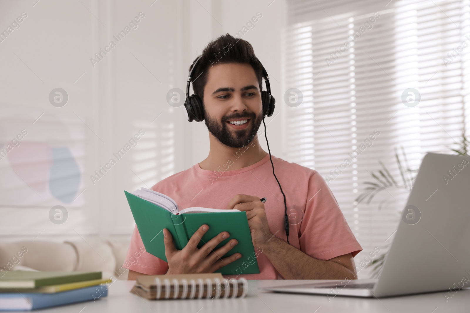 Photo of Young man watching webinar at table in room