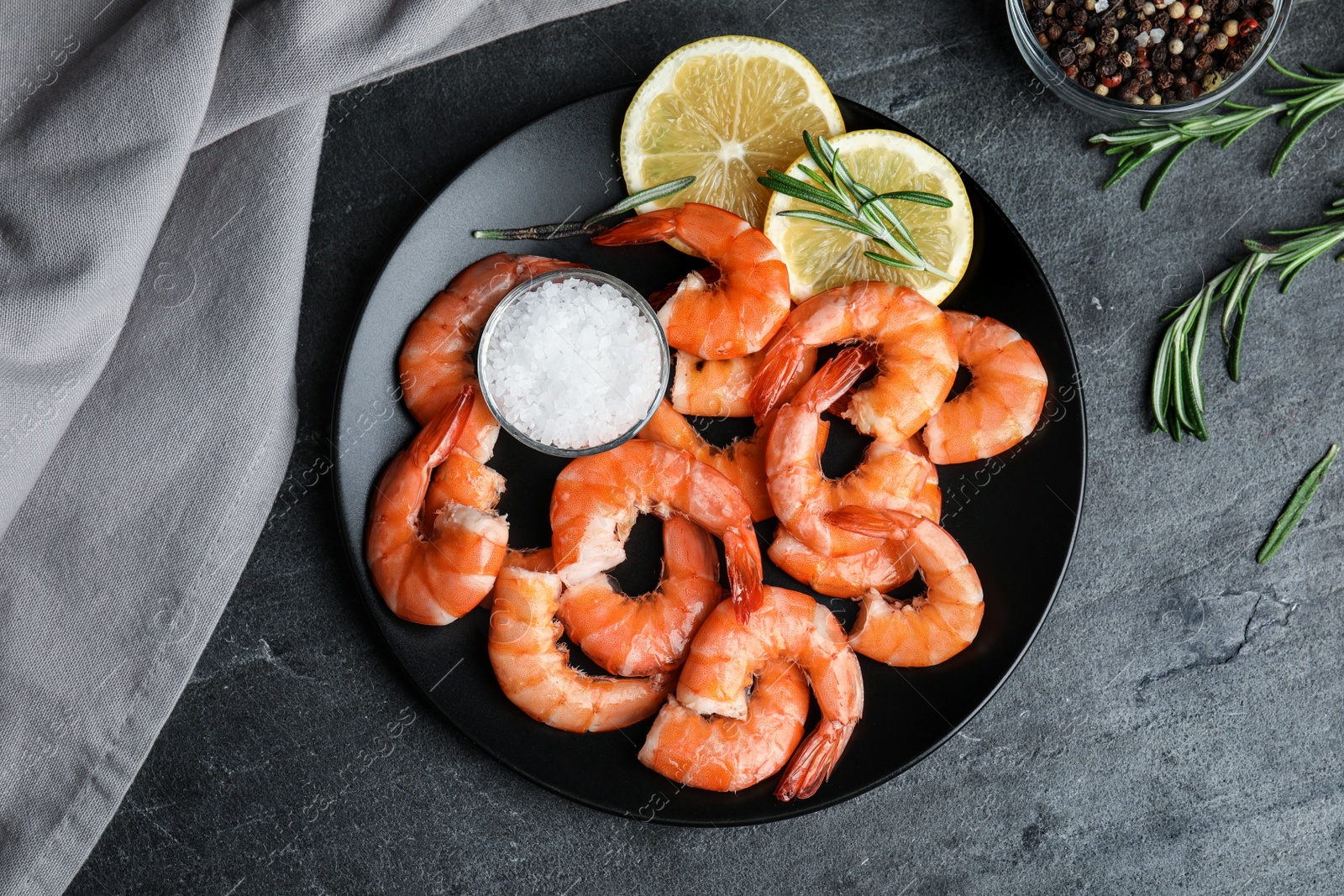 Photo of Delicious cooked shrimps with lemon and salt on dark grey table, top view