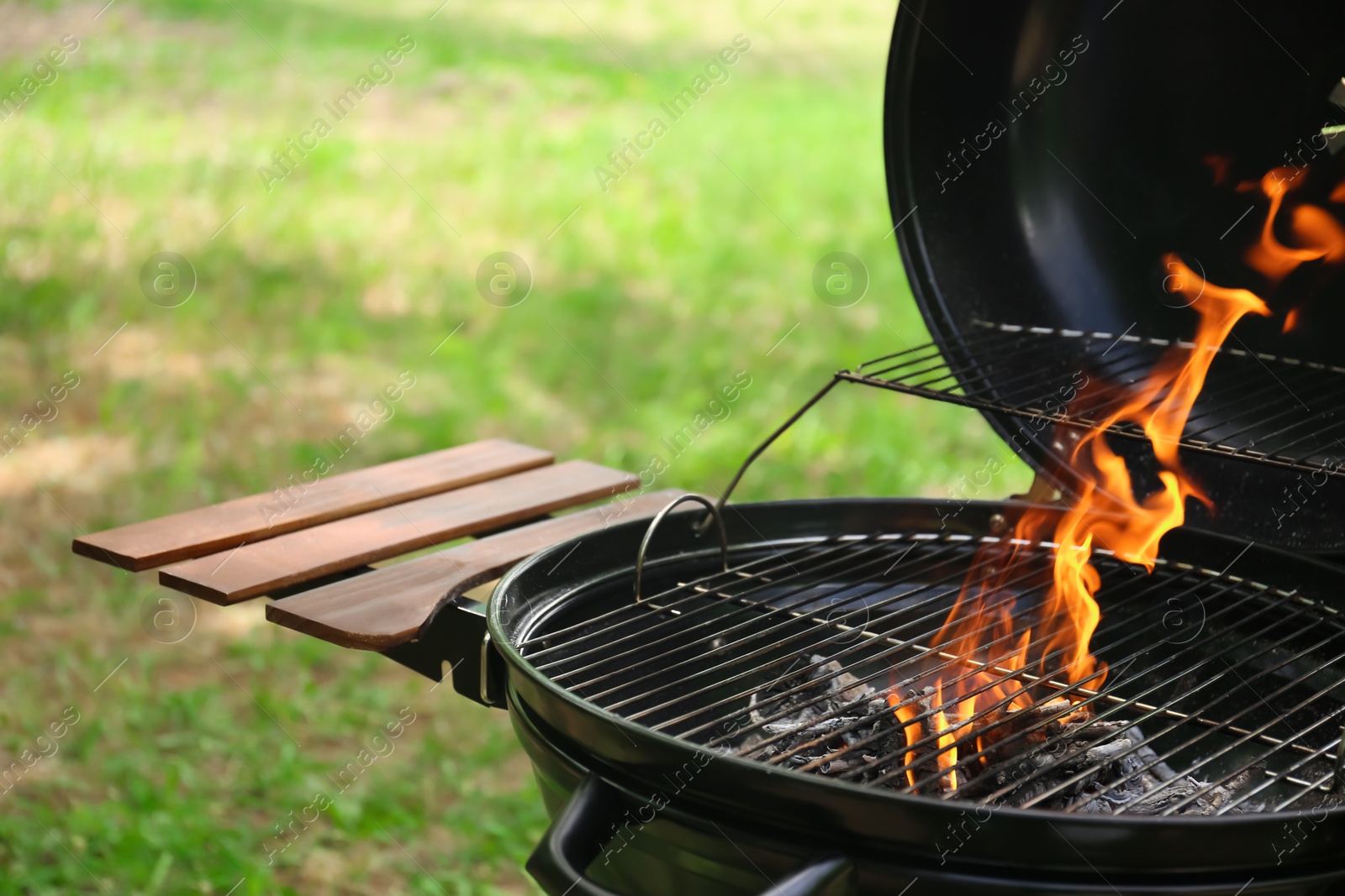 Photo of Modern barbecue grill with fire flames outdoors, closeup