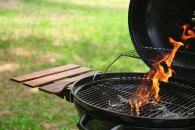 Photo of Modern barbecue grill with fire flames outdoors, closeup