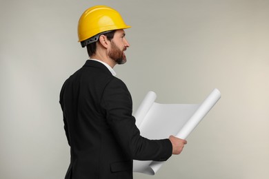 Photo of Architect in hard hat with draft on gray background