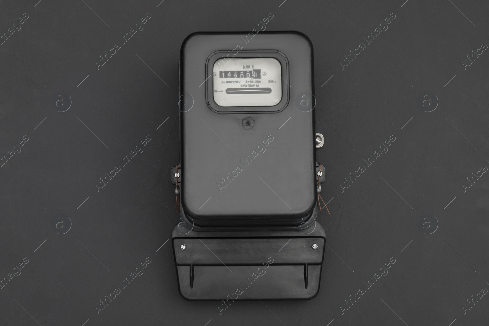 Photo of Electric meter on black background, top view. Measuring device