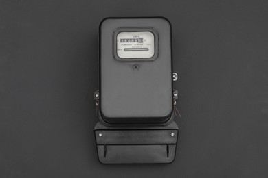 Photo of Electric meter on black background, top view. Measuring device