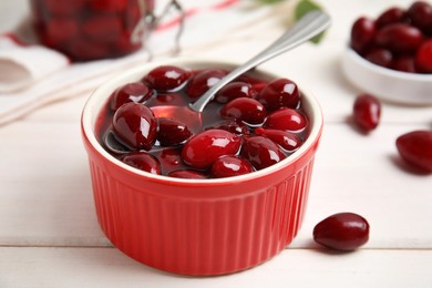 Delicious dogwood jam with berries and spoon on white wooden table, closeup