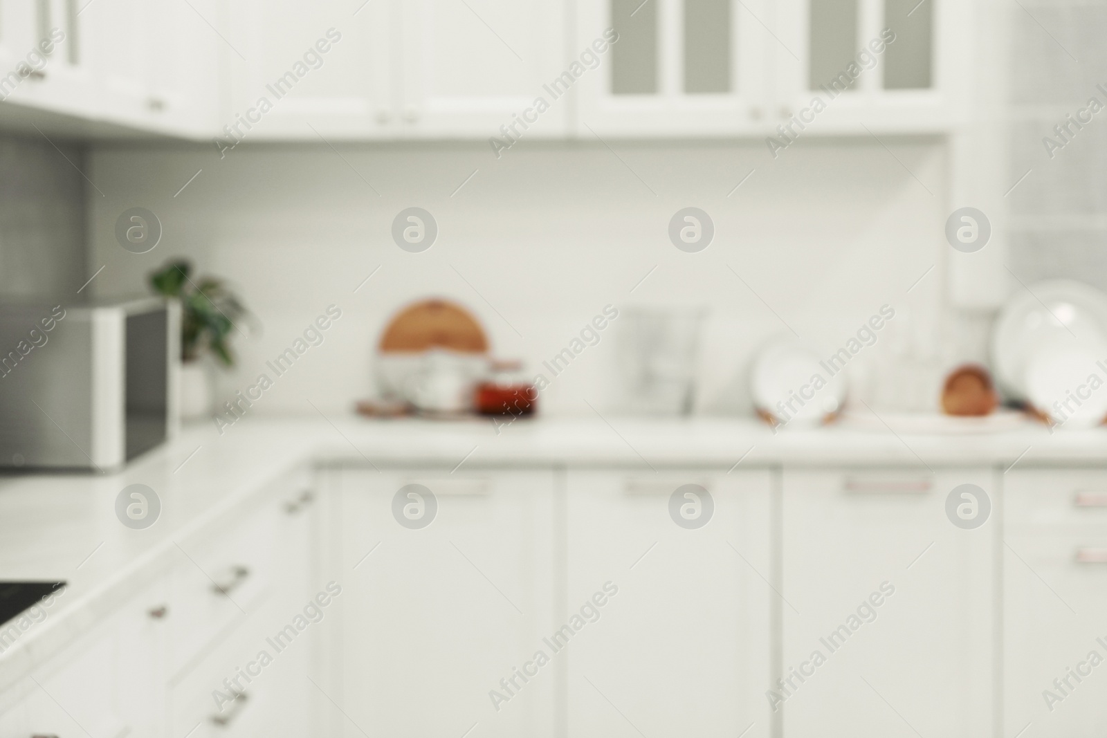 Photo of White stylish kitchen with furniture, blurred view. Interior design