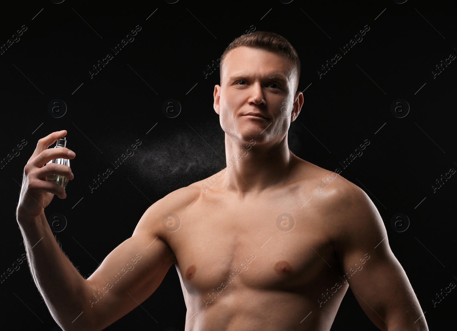 Photo of Handsome man using perfume on black background