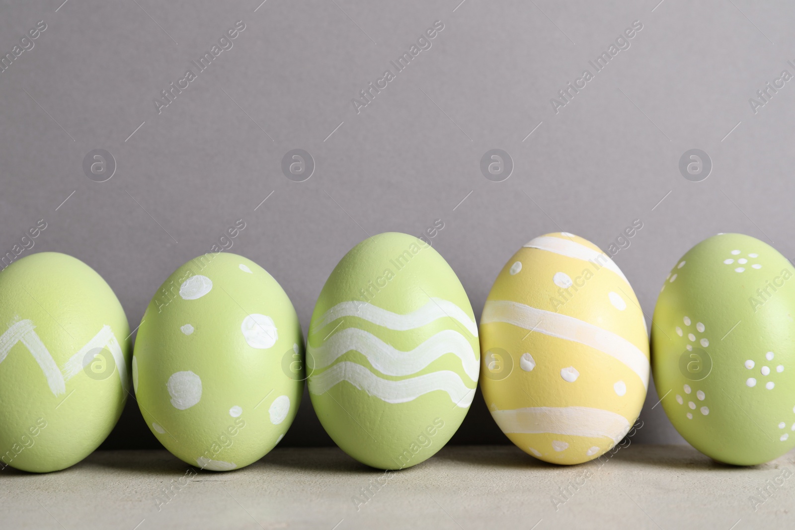 Photo of Painted Easter eggs on table against color background, space for text