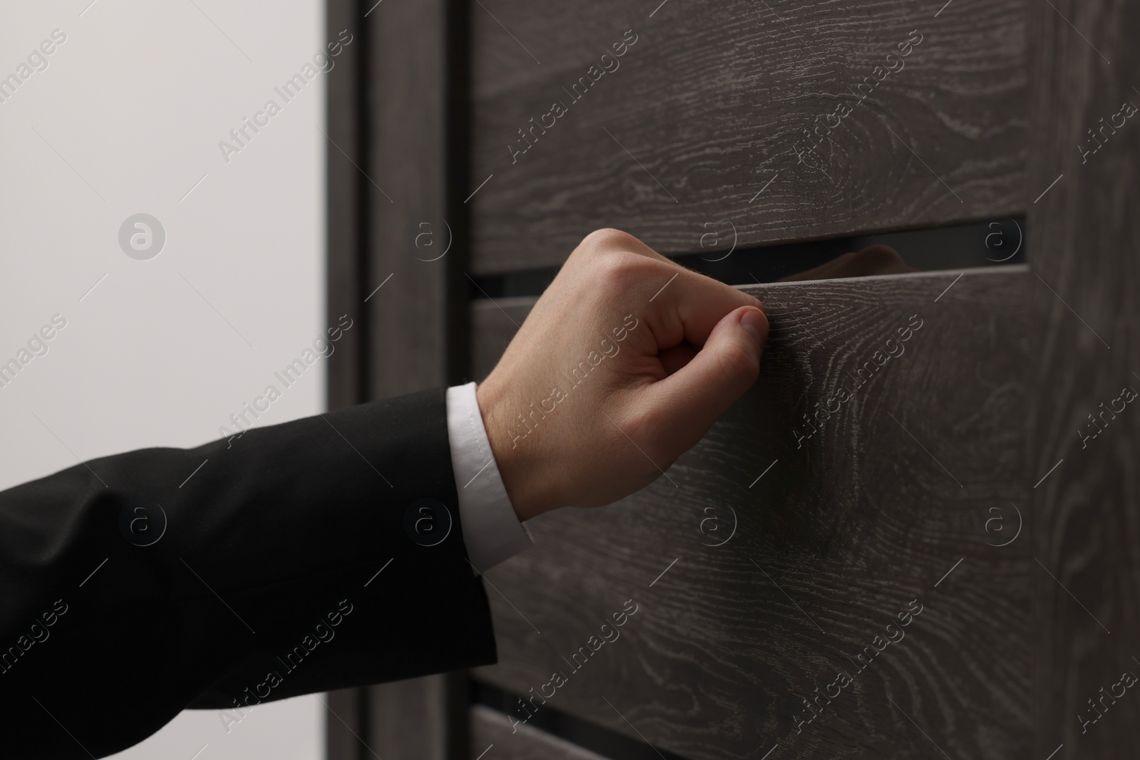 Photo of Collector knocking on door indoors, closeup view